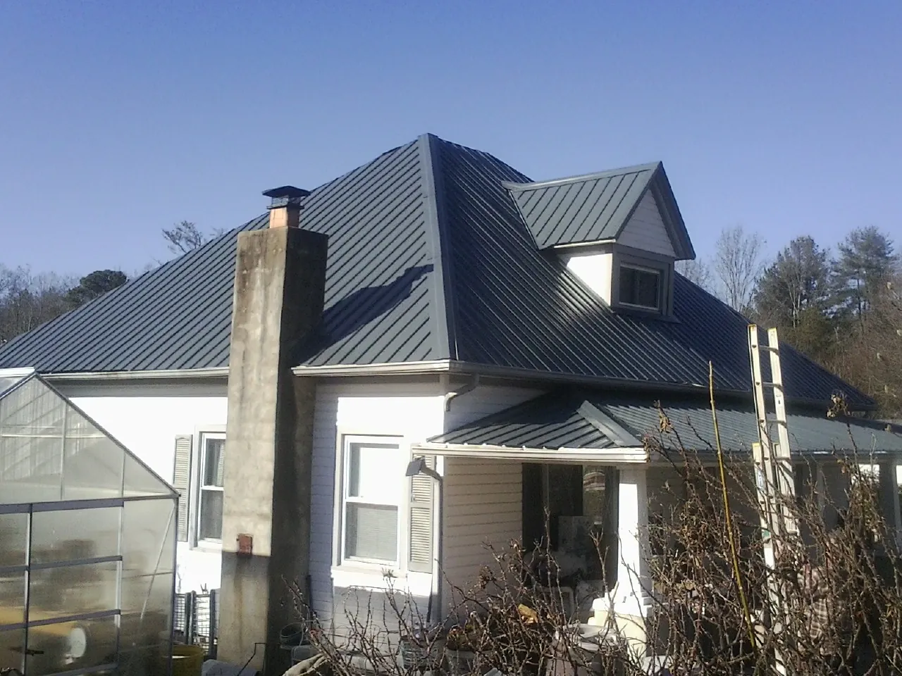 Dark blue standing seam metal roof on a white farmhouse with dormer — Slate & Tile Roof Repair by Roofing Brothers in Saugus