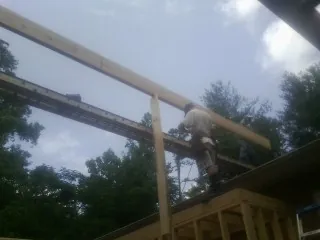 Carpenter setting a ridge beam over a new addition frame — Ice Dam Removal by Roofing Brothers in Saugus