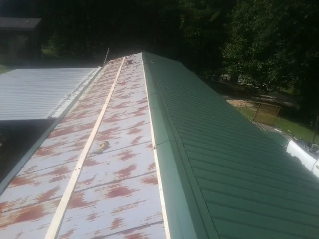 Old rusted panels beside newly installed green metal roofing — Wind Damage Roof Repair by Roofing Brothers in Saugus