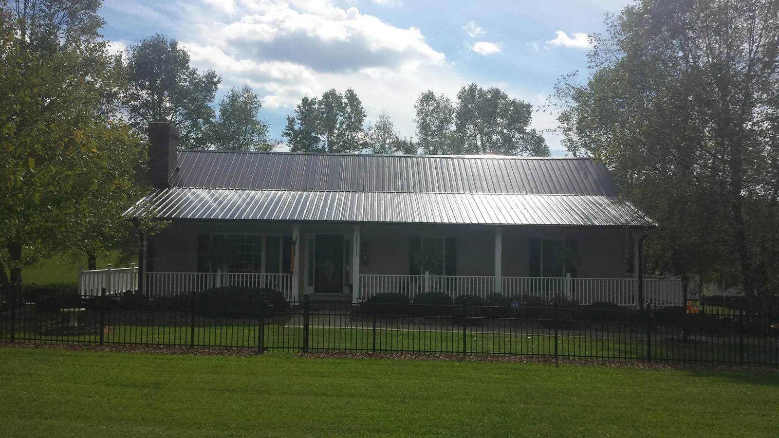 Gray metal roof on a brick ranch with a full width front porch — Gutter Guard Installation work by our crew in Saugus