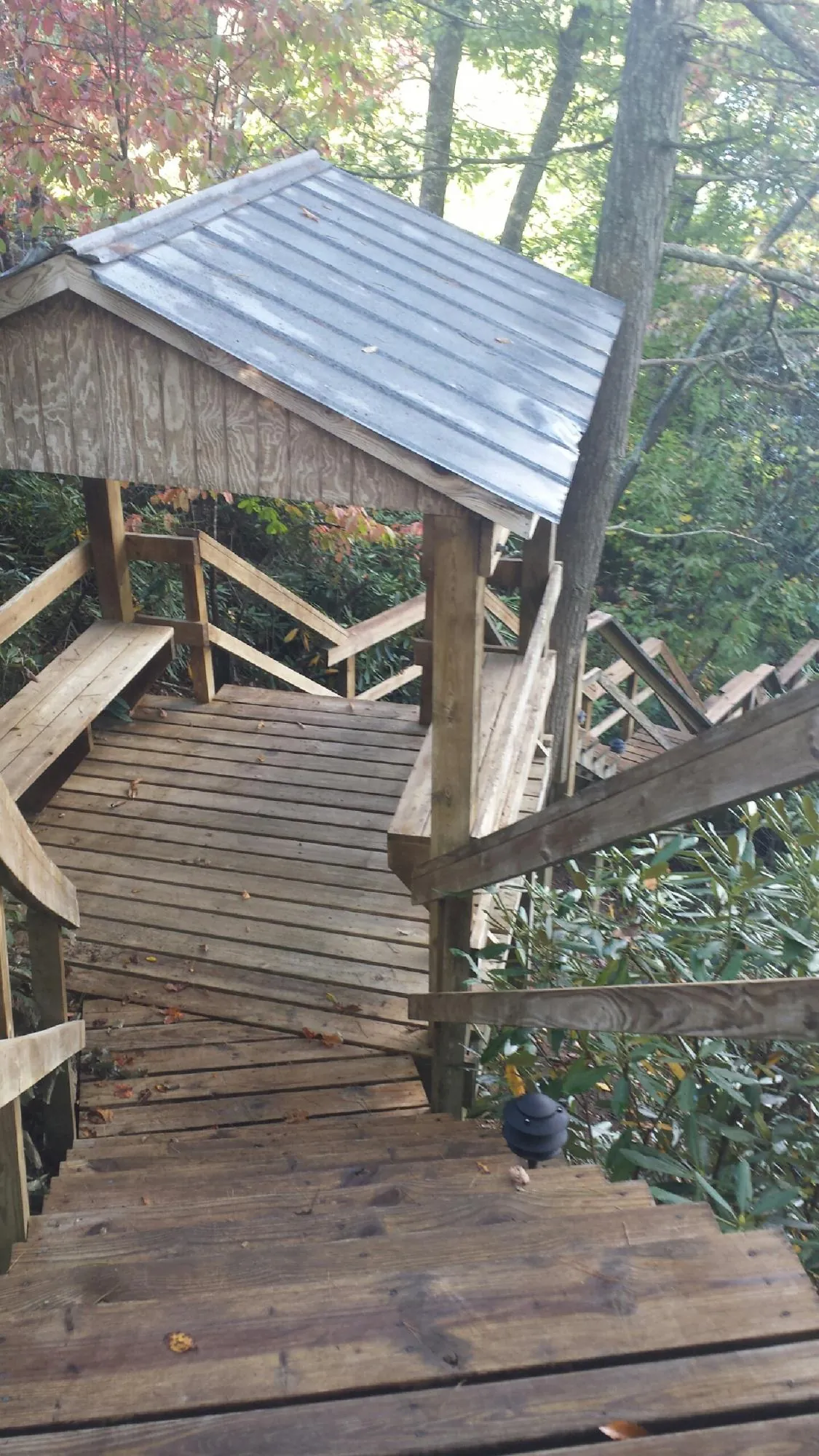 Metal roofed shelter over wooden steps on a wooded walkway — Skylight Repair & Installation work by our crew in Saugus