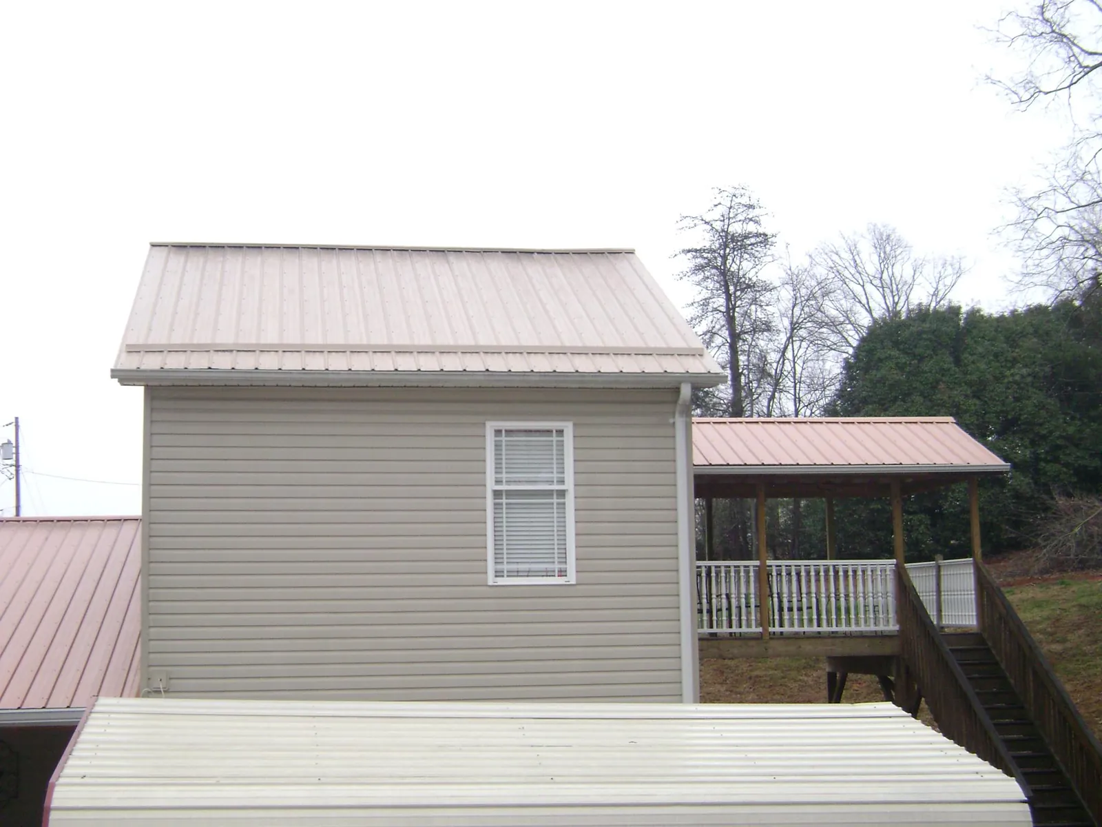 Tan metal roofs on a two story addition and attached porch, from a Roof Replacement job in Saugus