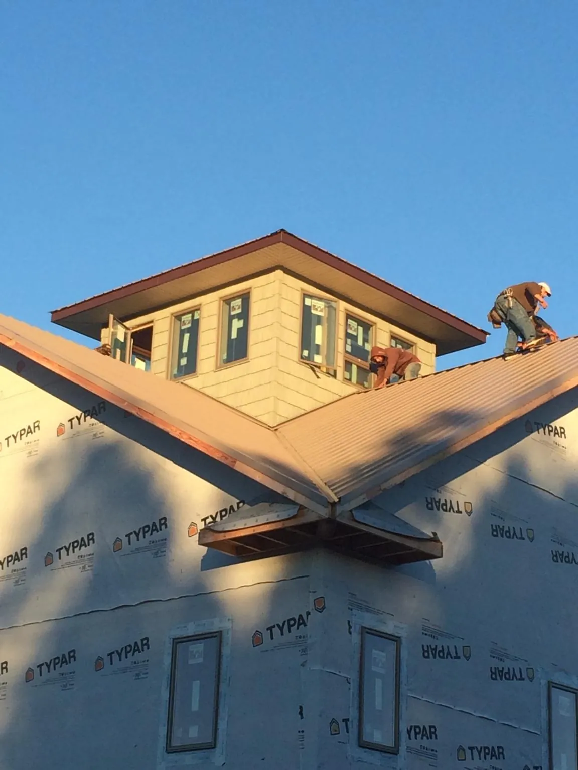 Roofers working around a rooftop cupola on a new metal roof at sunset — Roof Waterproofing in Saugus by Roofing Brothers
